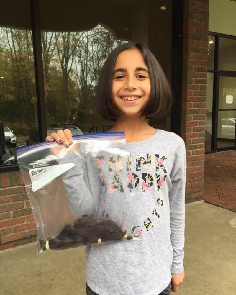 Ava holding a bag of donated hair in 2017